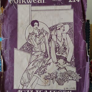 May include: A vintage Folkwear sewing pattern packet, featuring a purple cover with the text "Folkwear 214" and an illustration of two women in 1920s dresses. The pattern is for a "1927 Tea Frock" with sleeve options.