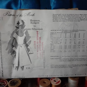 May include: A vintage sewing pattern for a dress, featuring a line drawing of a woman wearing a dress with a bow. The pattern is titled "Pattern of the Month" and is by Shannon Rodgers for Jerry Silverman. The pattern number is 135.