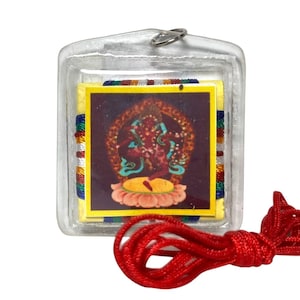 Puede incluir: Un colgante cuadrado encerrado en plástico transparente. El colgante presenta una imagen colorida de una deidad sobre una flor de loto. La imagen está rodeada por un borde amarillo y adornos coloridos. Un cordón rojo está unido al colgante.