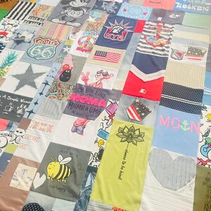 Könnte beinhalten: Eine Patchwork-Decke aus verschiedenen T-Shirt-Stoffen mit diversen grafischen Drucken, darunter Mickey Mouse, Route 66, die Freiheitsstatue, der Rosarote Panther, Snoopy, eine Hummel sowie Texte wie Moma Mama & Oma und choose to be kind.