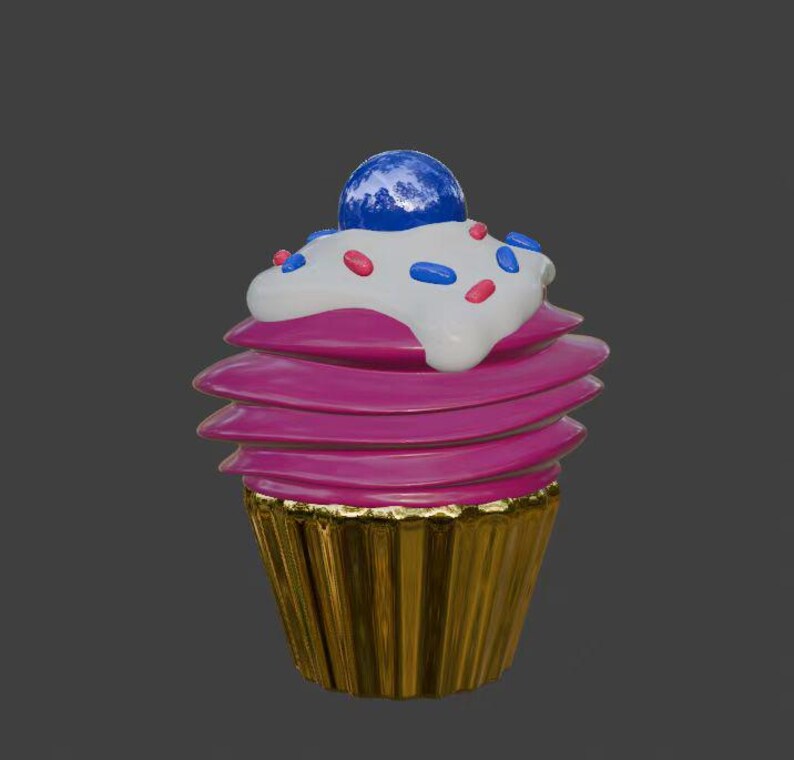 Puede incluir: Un cupcake rosa con glaseado blanco y chispas de colores. El cupcake est&aacute; cubierto con un caramelo azul y tiene una base de cupcake dorada.