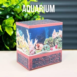 May include: A miniature cardboard aquarium with a colorful coral reef scene. The aquarium is decorated with a brown, ornate base.