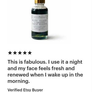 Pu&ograve; includere: Un flacone contagocce in vetro trasparente contenente un liquido blu scuro, sormontato da un collare dorato e da un bulbo in gomma bianca. L'etichetta bianca riporta il testo Blue Tansy & Squalane Face Serum in caratteri neri sul davanti.
