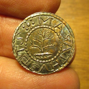 May include: A silver coin with a tree design and the inscription "IMAS" around the edge.