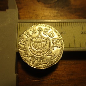 May include: A gold coin with a ship design and the inscription "REX EGBL" around the edge.