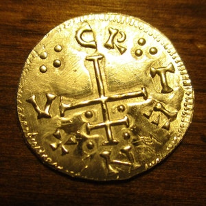 May include: A gold coin with a cross and the letters "C.R.T." and "V." on it.