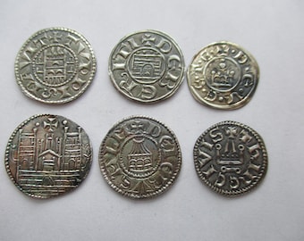 May include: Six antique silver coins with detailed designs. The coins feature various embossed images, including buildings, crowns, and intricate patterns. The coins are arranged on a light-colored surface, showcasing their historical and collectible nature.