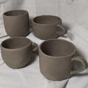 May include: Four brown ceramic mugs with handles. The mugs are unglazed and have a rustic appearance.