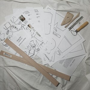 May include: A set of pottery mug templates, tools, and wooden rulers for making mugs. The templates include instructions for making a mug, a cylinder, and a square. The tools include a pottery rib, a needle tool, a wooden tool, and a metal tool. The wooden rulers are 12 inches long.