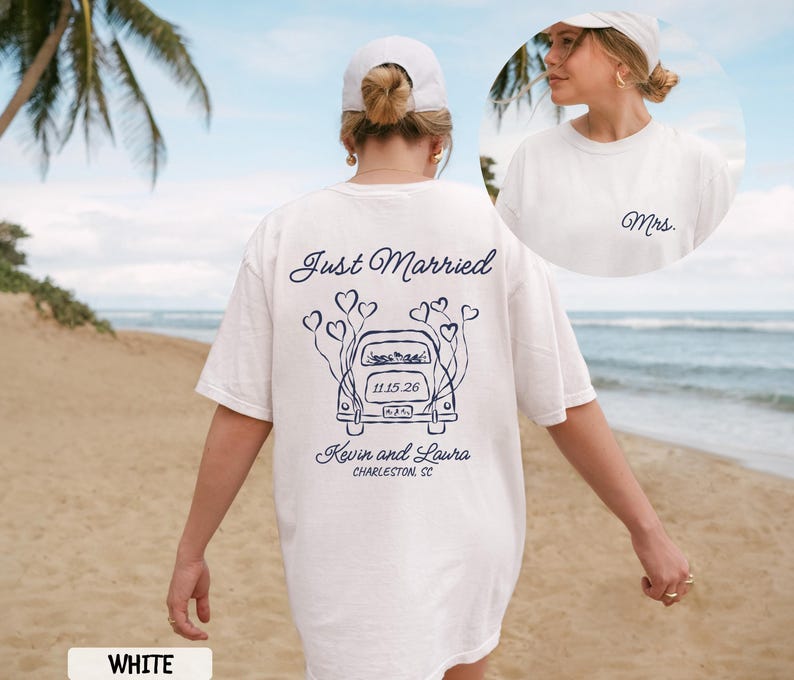 May include: White t-shirt with a navy blue graphic that says "Just Married" and features a car with heart-shaped balloons. The shirt also includes the names "Kevin and Laura" and the date "11.15.26" and the location "Charleston SC".