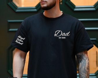 May include: Black t-shirt with white text that reads "Dad Est 2025". The left sleeve has white text that reads "Abigail Sophia Michael".