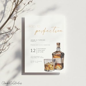 Puede incluir: Una tarjeta de invitación blanca con texto dorado que dice "Aged to Perfection". La tarjeta presenta una ilustración de acuarela de una botella de whisky y un vaso con hielo. El texto dice "¡Adam cumple cuarenta!" e incluye detalles del evento.