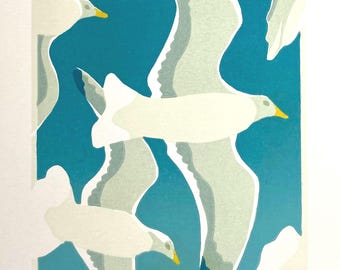 May include: A print featuring stylized white seagulls in flight against a teal and blue background. The birds have gray and white wings with yellow beaks. The artwork has a minimalist, graphic style.