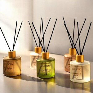 May include: Five glass bottles with gold lids and black diffuser sticks. The bottles are filled with a clear liquid and have labels that say "July Wind" and "Scent Diffuser".