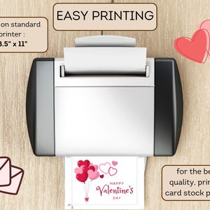 May include: A printer with a sheet of paper in it, showing a printable Valentine's Day card with red and pink heart balloons. The text on the card reads "Happy Valentine's Day". The printer is on a wooden surface. The text "EASY PRINTING" is written on a brown rectangle above the printer. The text "print on standard printer: 8.5" x 11" is written on a brown rectangle to the left of the printer. The text "for the best quality, print on card stock paper!" is written on a brown rectangle to the right of the printer.