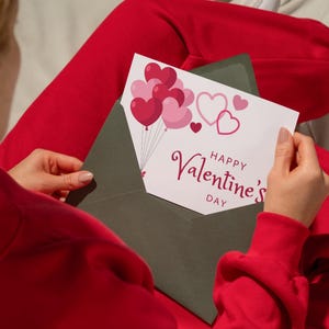 May include: A white card with a red envelope. The card has a pink and red heart balloon design and the text "Happy Valentine's Day".