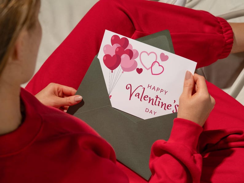 May include: A white card with a red envelope. The card has a pink and red heart balloon design and the text "Happy Valentine's Day".