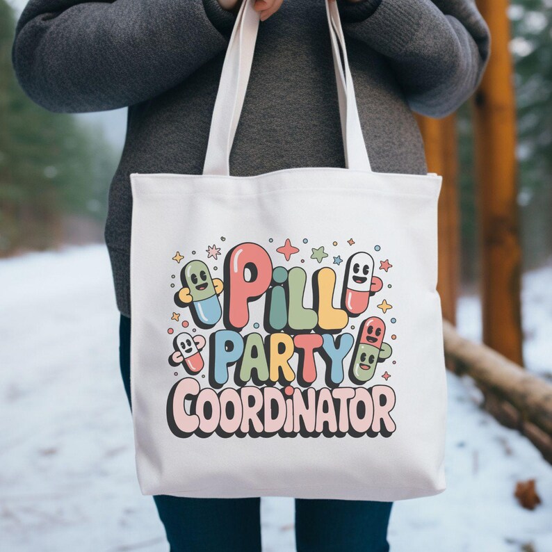 May include: White tote bag with the text "Pill Party Coordinator" in colorful, retro-style lettering. The design includes cartoon pill characters and stars. The bag is held by a person wearing a gray sweater.