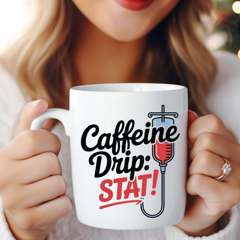 May include: White ceramic mug with the words "Caffeine Drip: STAT!" in black and red. The mug features a graphic of an IV drip bag with red liquid, blue liquid, and a black tube. The mug has a white handle.