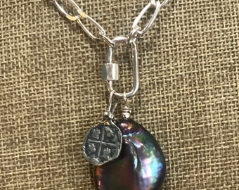 May include: A silver chain necklace with a large, dark iridescent pearl pendant and a small silver charm with a cross design.