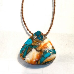 May include: A turquoise, orange, and white gemstone pendant on a brown cord necklace. The pendant is a teardrop shape and has a unique, marbled pattern.