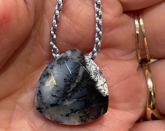 May include: A silver cord necklace with a black and white dendritic agate pendant. The pendant is a triangular shape with a pointed tip.