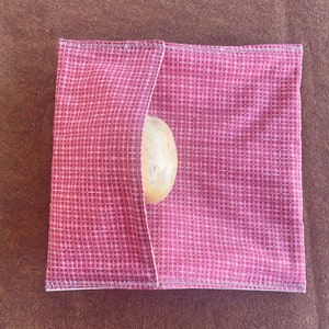 May include: A red and white gingham fabric pouch with a single potato inside.