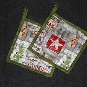May include: Two green and white Christmas pot holders with a variety of holiday-themed designs, including "Joy", "Peace on Earth", and "Christmas".
