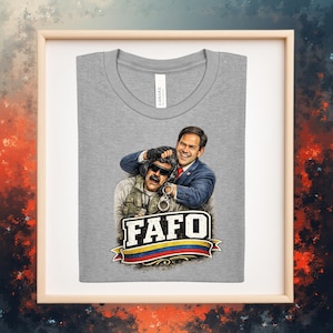 Puede incluir: Una camiseta gris con un gráfico de dos hombres, uno con traje y otro con chaleco militar, con la palabra "FAFO" en negrita. El gráfico incluye una pancarta colorida con un diseño de bandera.