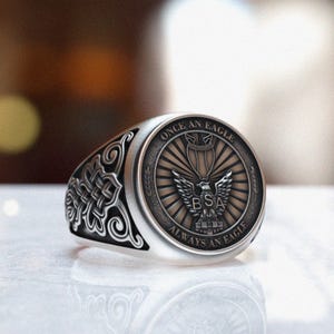 May include: A silver ring with a detailed design featuring an eagle and the text "Once an Eagle Always an Eagle" and "BSA".