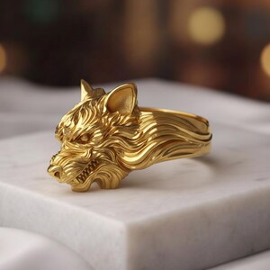 May include: A gold-colored ring featuring a detailed wolf head design. The ring showcases the wolf's face with intricate fur and teeth details. The ring is displayed on a white marble surface, highlighting the jewelry's craftsmanship.