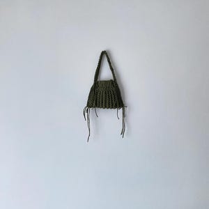 May include: A small, green crocheted handbag with long, thin straps.