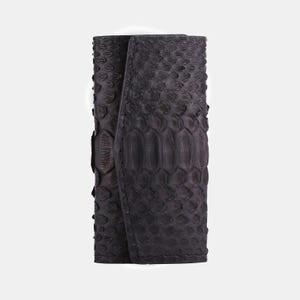 Könnte beinhalten: Eine schwarze Lederbörse mit Schlangenhautmuster.