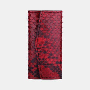 May include: A red snakeskin key holder with a black stitching detail.