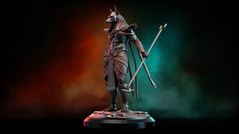 May include: A detailed statue of Anubis, the Egyptian god of the afterlife, depicted with a jackal head and human body. The figure is holding a staff and scepter, standing on a round base. The statue is dark with bronze and purple accents.