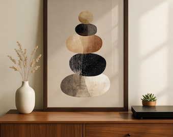 May include: Framed abstract art print featuring a stack of oval shapes in shades of brown, black, and beige. The artwork is displayed on a wooden cabinet, with a vase of dried flowers and a small succulent plant nearby. The frame is dark brown.