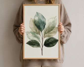 Könnte beinhalten: Ein gerahmter Wandkunstdruck mit einer Aquarellillustration eines belaubten Zweigs in verschiedenen Grün- und Salbeitönen auf hellcremefarbenem Hintergrund. Das Kunstwerk ist in einem schlichten, hellen Holzrahmen mit sauberer Kante gefasst.