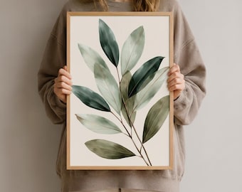 Könnte beinhalten: Ein rechteckiger Wandkunstdruck in einem hellen Holzrahmen mit einer botanischen Illustration eines belaubten Zweigs. Das Kunstwerk zeigt längliche Blätter in verschiedenen Schattierungen von tiefem Waldgrün, Salbei und Oliv auf cremefarbenem Grund.