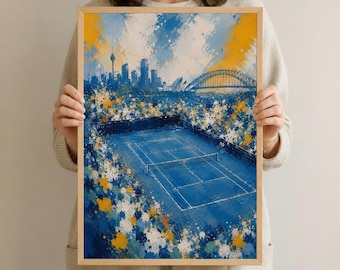 May include: A framed art print depicting a tennis court with a cityscape backdrop. The artwork features a blue court, a yellow bridge, and a skyline in shades of blue and yellow. The print is held by a person.