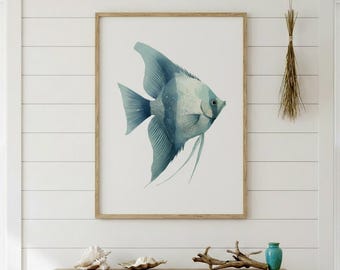 May include: A framed watercolor print of a blue and white angelfish. The artwork is displayed in a light brown wooden frame against a white background. The fish has detailed fins and long, flowing filaments. The overall theme is coastal decor.