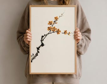 Könnte beinhalten: Ein gerahmter Kunstdruck mit einer Tuschemalerei eines blühenden Zweigs. Der Zweig ist mit schwarzen Tuschestrichen dargestellt, ergänzt durch zarte, warm orangefarbene Blüten auf einem hellen, cremefarbenen Hintergrund.