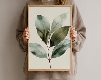 Könnte beinhalten: Ein gerahmter Wandkunstdruck mit einer Aquarellillustration eines blättrigen Pflanzenzweigs mit mehreren grünen Blättern in verschiedenen Salbei- und Waldgrüntönen vor einem schlichten, hell cremefarbenen Hintergrund in einem hellen Holzrahmen.