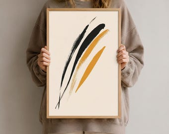 Könnte beinhalten: Ein rechteckiges gerahmtes Wandbild mit cremefarbenem Hintergrund und drei diagonalen, strukturierten Pinselstrichen in Schwarz und Senfgelb. Das Kunstwerk befindet sich in einem hellen Holzrahmen mit einem schlichten, klaren Rand.