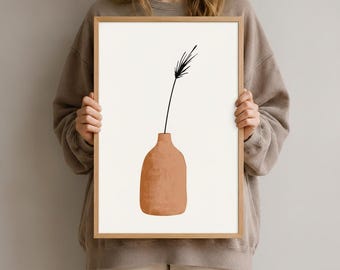 Könnte beinhalten: Ein gerahmter Kunstdruck mit einer terrakottafarbenen Vase mit rundem Boden und einer einzelnen dünnen schwarzen Strichzeichnung eines Pflanzenstängels mit Blättern, die aus der Öffnung nach oben ragen, vor einem cremeweißen Hintergrund.