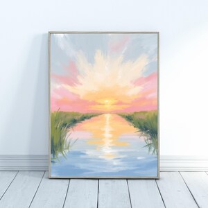 May include: A framed landscape painting depicting a sunset over a waterway. The artwork features a vibrant sky with pink, yellow, and orange hues, reflecting in the water. Green grass lines the waterway's edges, creating a serene and colorful scene.