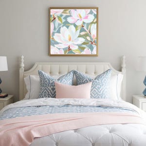 K&ouml;nnte beinhalten: Ein Schlafzimmer mit einem wei&szlig;en, getufteten Kopfteil, verziert mit gemusterten Kissen in Blau und Wei&szlig; und einem rosafarbenen Lendenkissen. Die Bettw&auml;sche umfasst eine blau-wei&szlig; gemusterte Bettdecke und eine rosa Decke. Ein gerahmter Blumendruck mit wei&szlig;en und rosa Bl&uuml;ten h&auml;ngt &uuml;ber dem Bett.