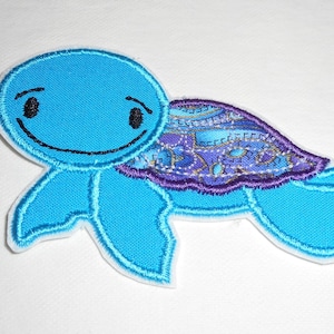 May include: A blue and purple embroidered patch of a smiling turtle with a patterned shell.