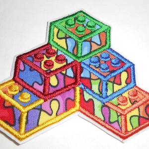 May include: Embroidered patch featuring a colorful stack of toy building blocks. Each block is a different color, including red, yellow, green, and blue, with a stained glass effect. The patch has a white border.