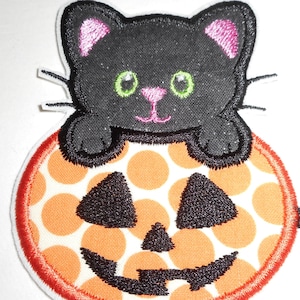 May include: Black cat with pink ears sitting on an orange and white polka dot pumpkin with a black jack-o-lantern face.