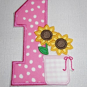 May include: Pink felt number one with white polka dots and a pink felt flower pot with two yellow felt sunflowers.